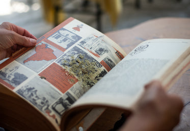 hands open a large book with a dried flower in the middle