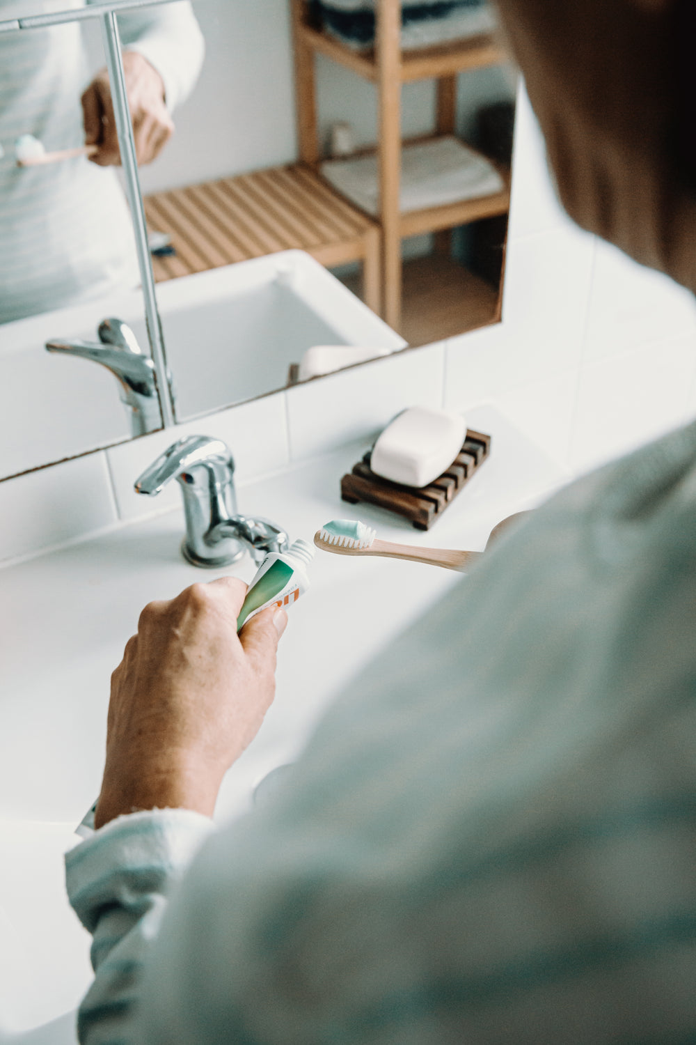 hands putting toothpaste on a toothbrush