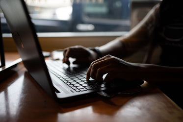 hands rest on a black laptop keyboard