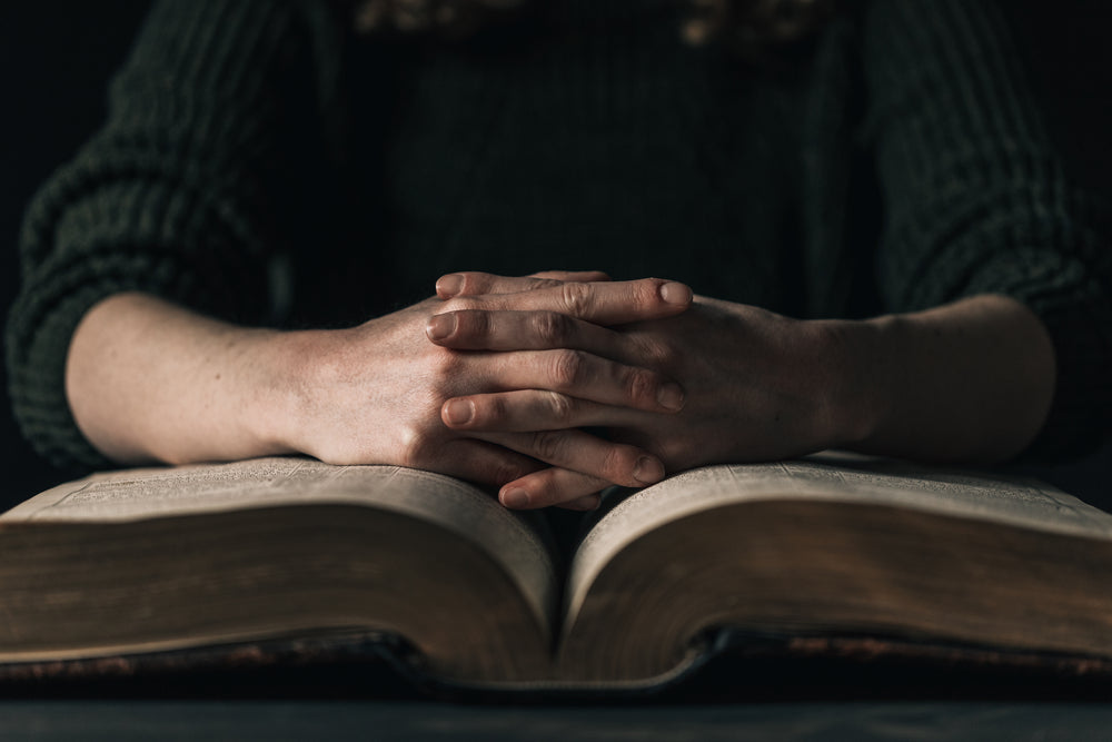 hands resting on open book