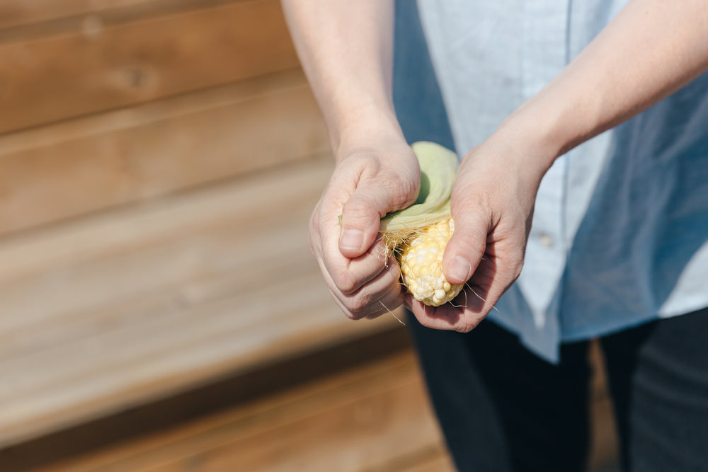 hands shucking corn