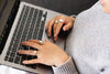 hands with gold rings type on a laptop