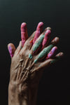hands with paint on them in front of a black background