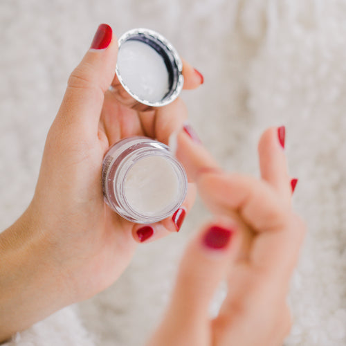 Hands With Red Nails Hold A Small Cosmetics Container