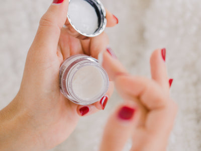 Hands With Red Nails Hold A Small Cosmetics Container