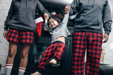 menino feliz balançando nos braços dos pais na manhã de natal