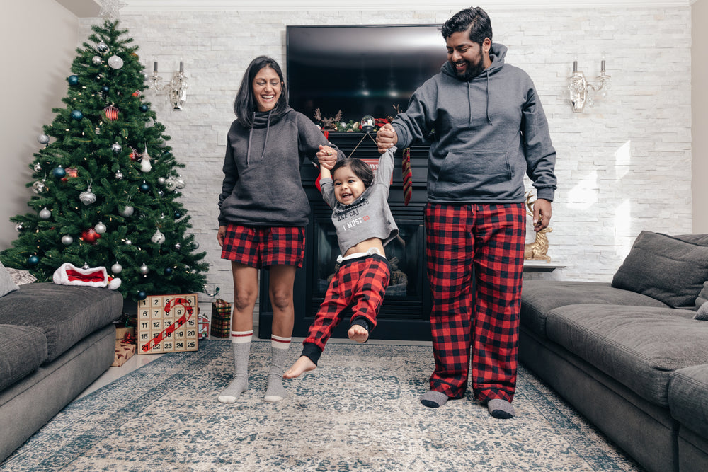 casal animado balança o filho nos braços na manhã de natal