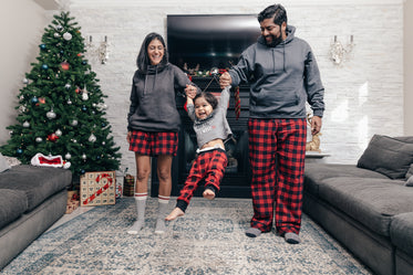 casal animado balança o filho nos braços na manhã de natal