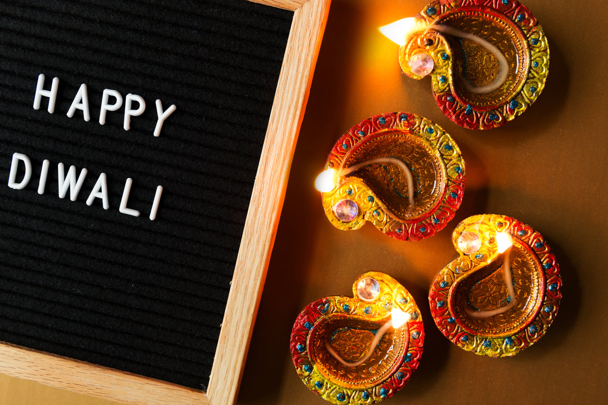 happy diwali sign laying beside four diya lamps