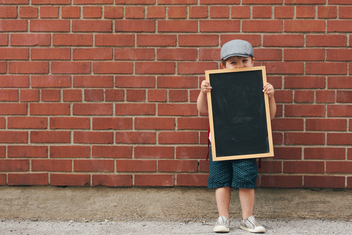 happy little boy holding blank chalkboard