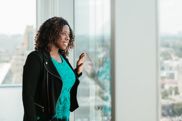 happy woman looking out woman from highrise office