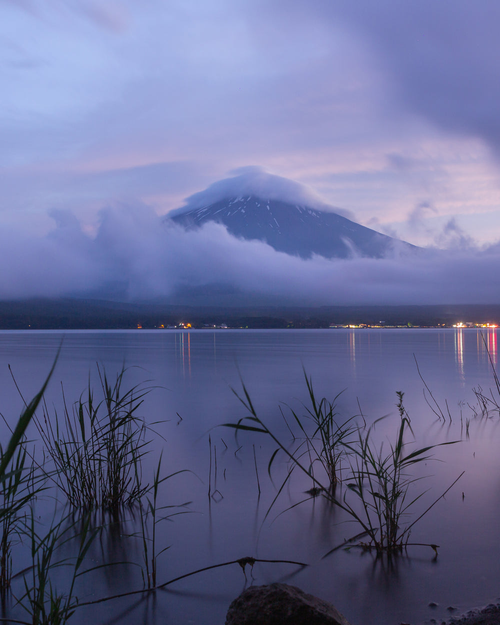 hazy blue water with mountain and wispy white clouds