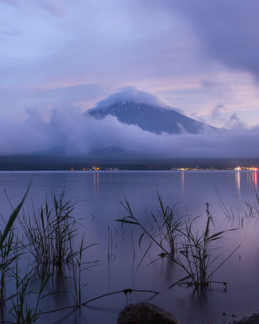 hazy blue water with mountain and wispy white clouds