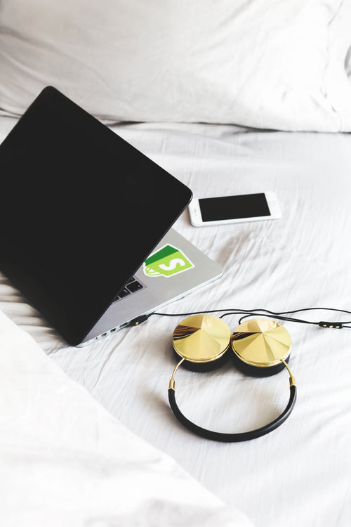 headphones and laptop on bed