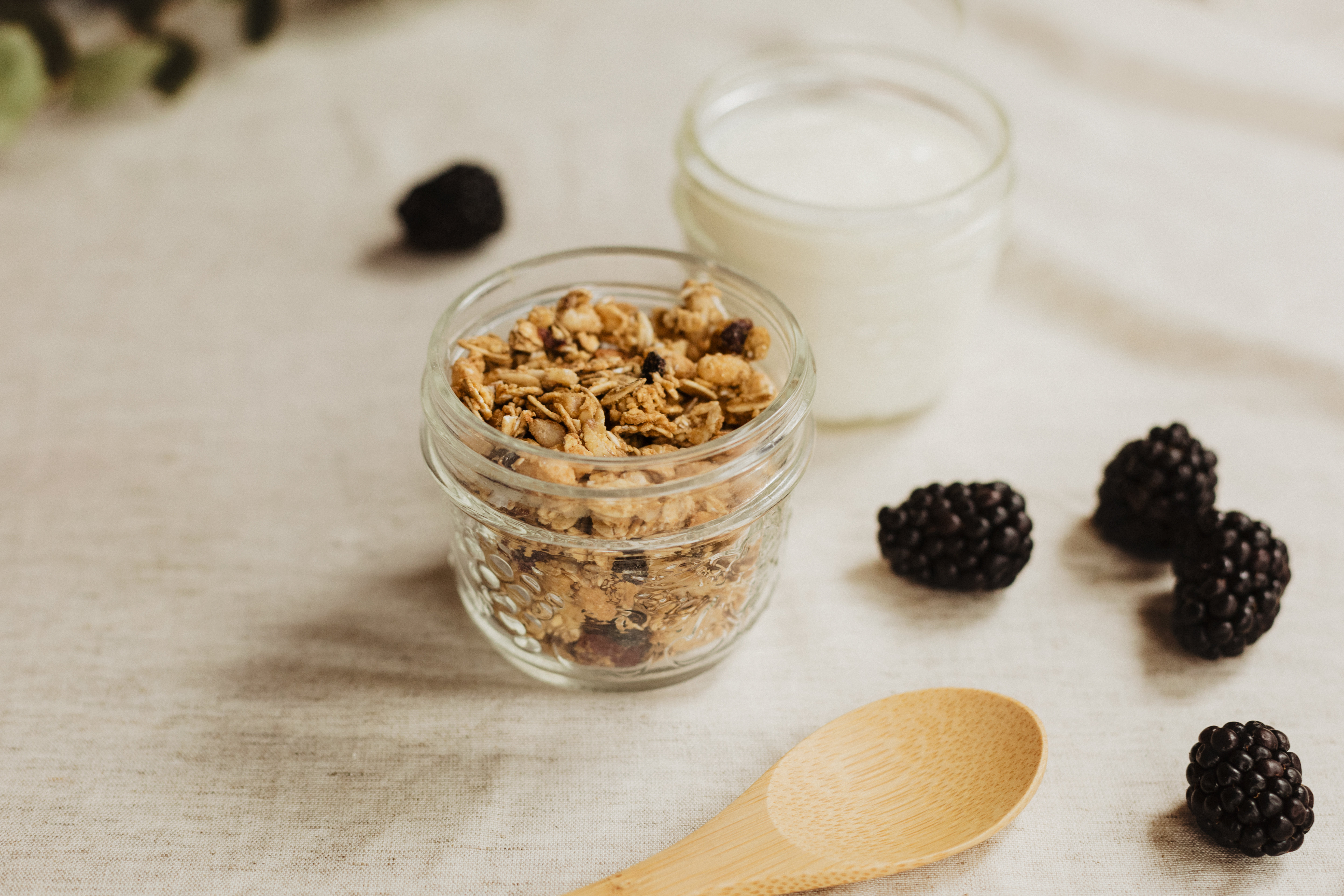 Pote de granola com iogurte e amoras frescas, uma opção saudável para café da manhã ou lanche.