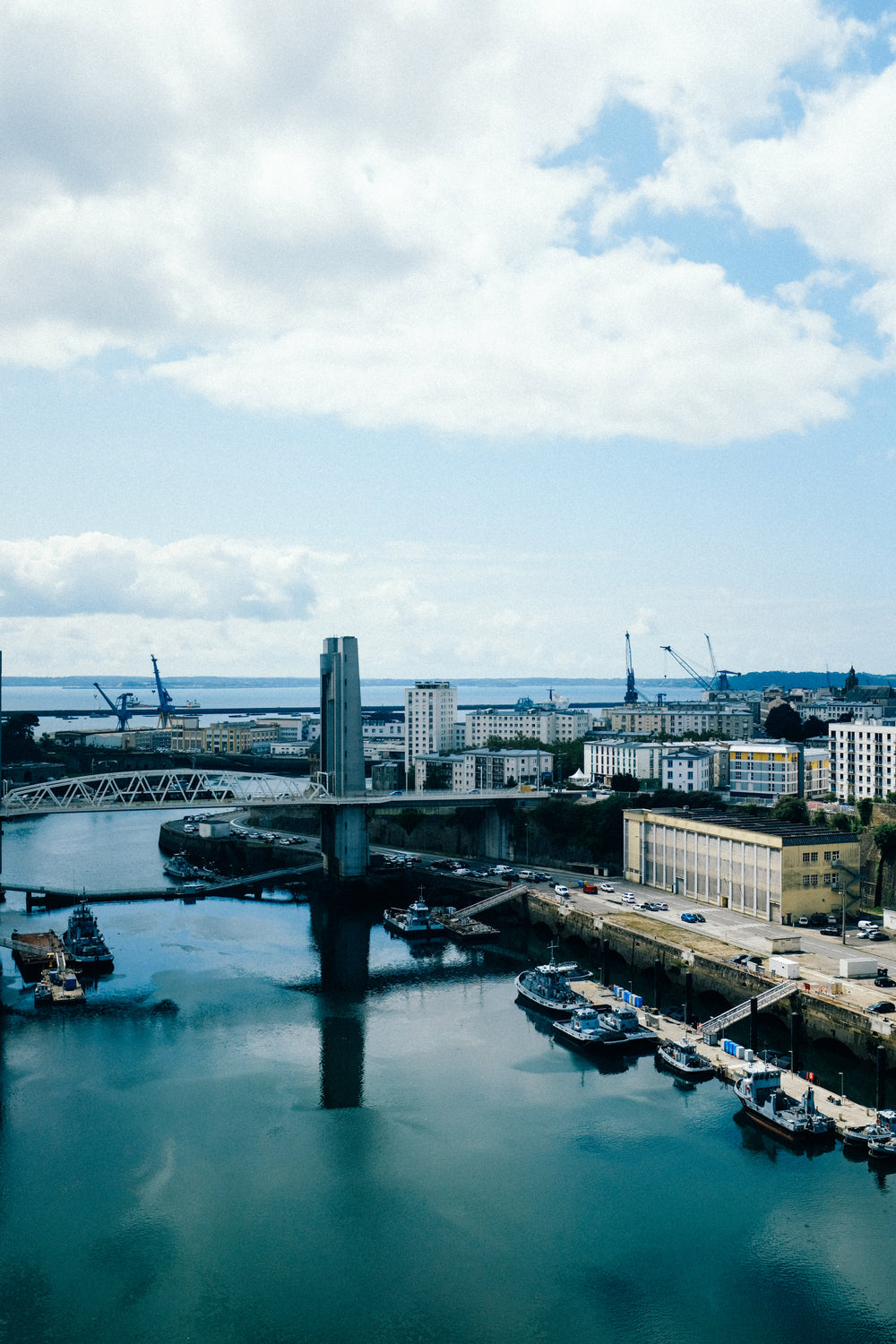 high view of city buildings by blue water and docked boats