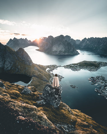 hiker looks out over bay surrounded by mountains