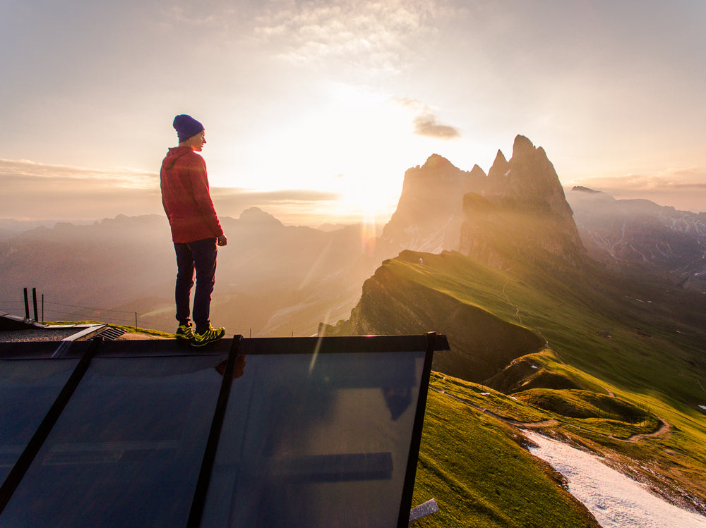 hiker looks out over view from mountain summit