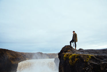 hiker on cliff by waterfall