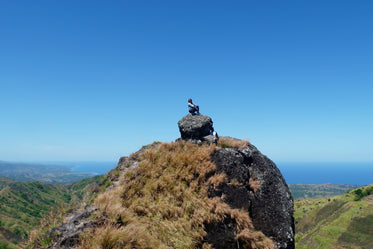 hiker rests on rock above landscape