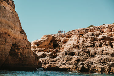 hikers atop a scarred hill near blue waters