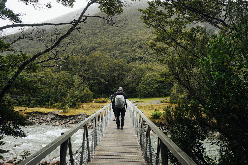 hikers cross rapids on walking  bridge