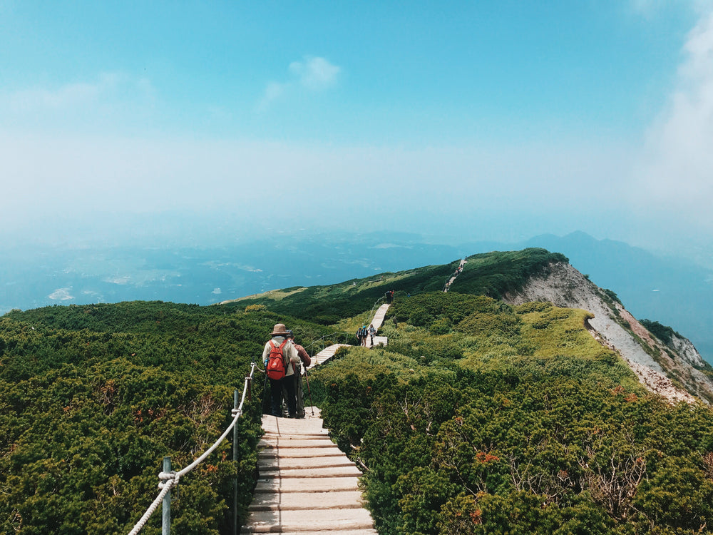 hikers trekking over green mountain tops