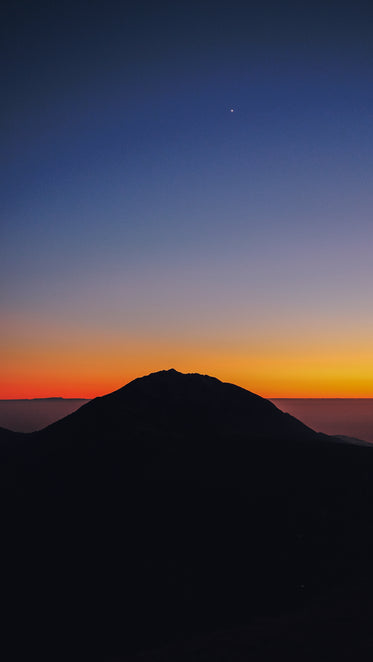 hilltop silhouetted by distant sunset