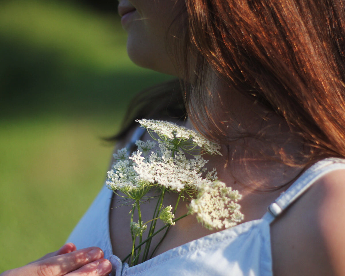 holding a bunch of queen annes lace to chest