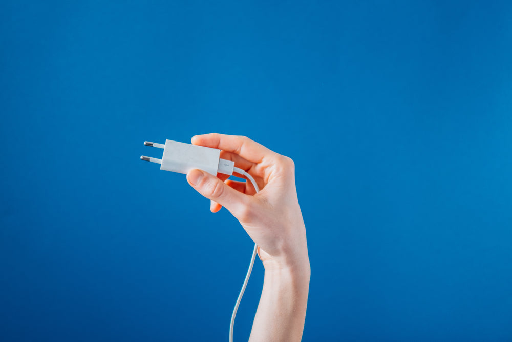 holding a white phone charger on blue