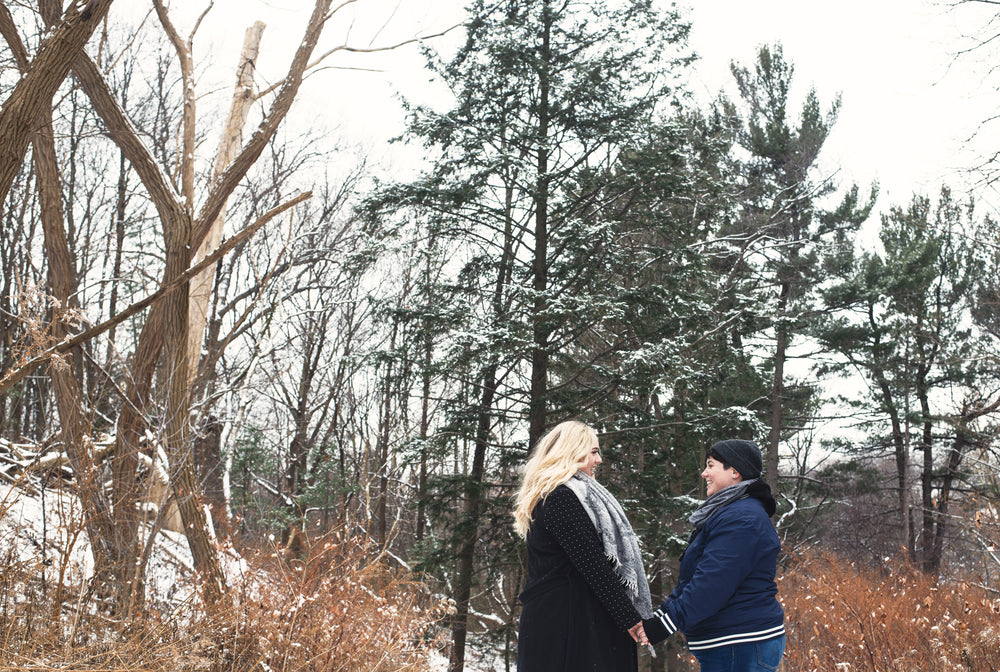 holding hands under snow capped trees