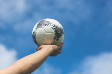 holding out soccer ball to the blue sky