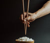 Holding Pair Of Chopsticks Over Bowl Of Rice