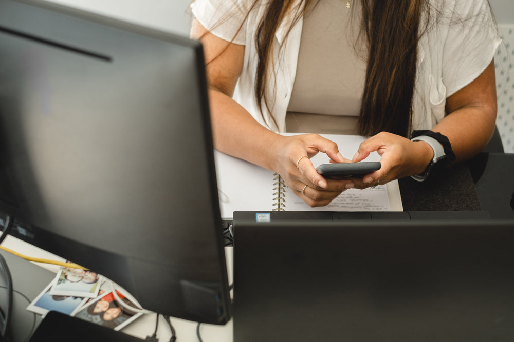 holding phone with both hands while sitting at desk