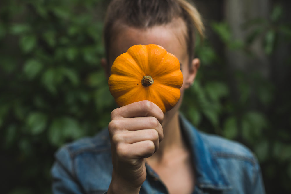 holding small pumpkin in front of face