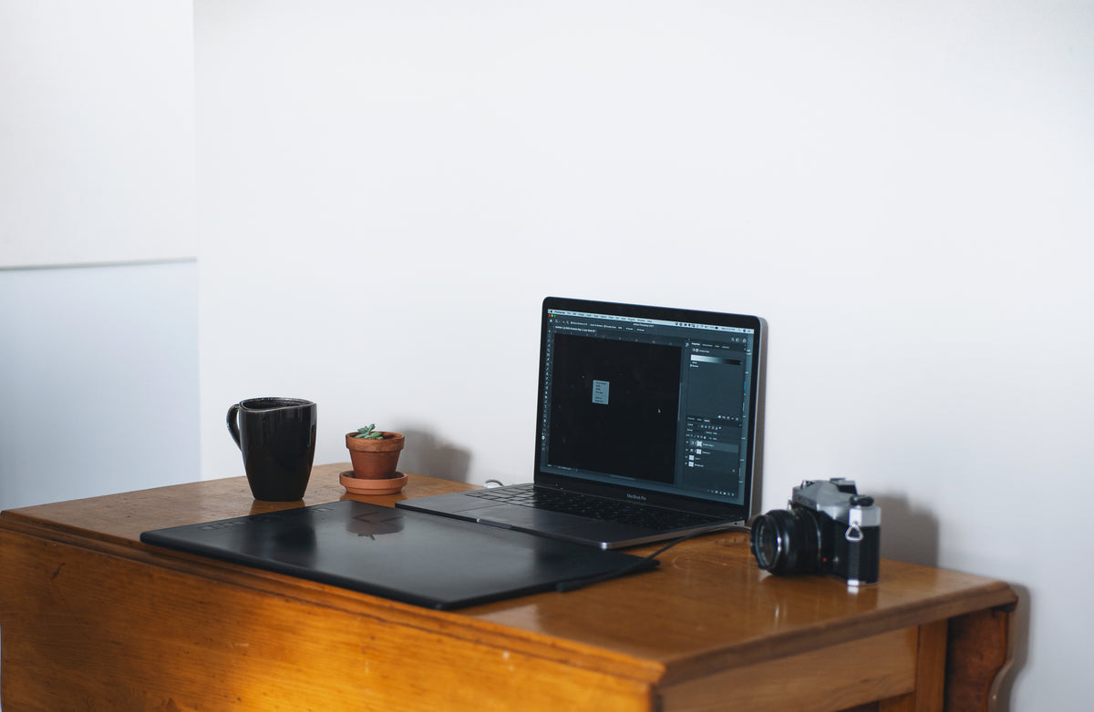home office with a laptop and film camera on wooden table