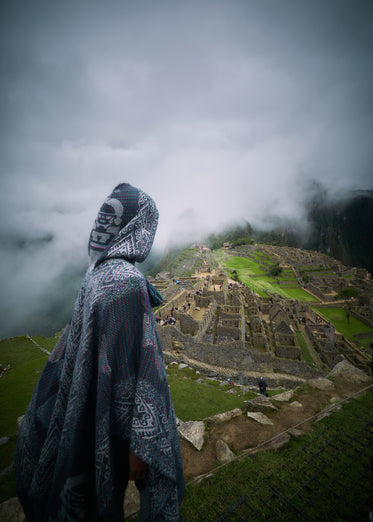 hooded person overlooking ruins