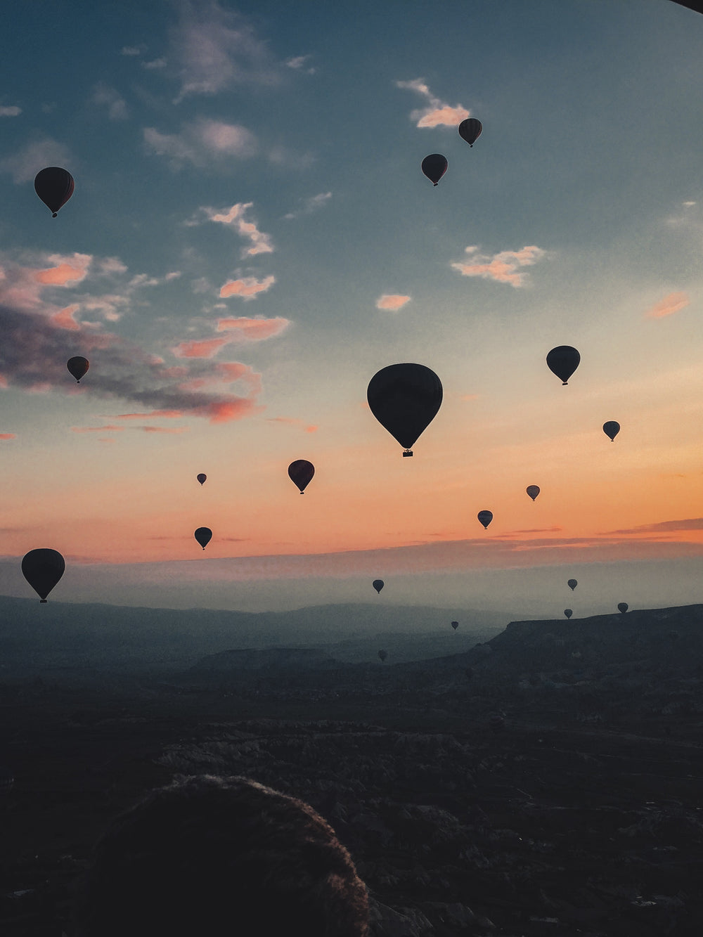 hot air balloons floating into the sunset