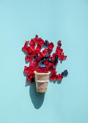 icecream cone with candy spilling out on blue background