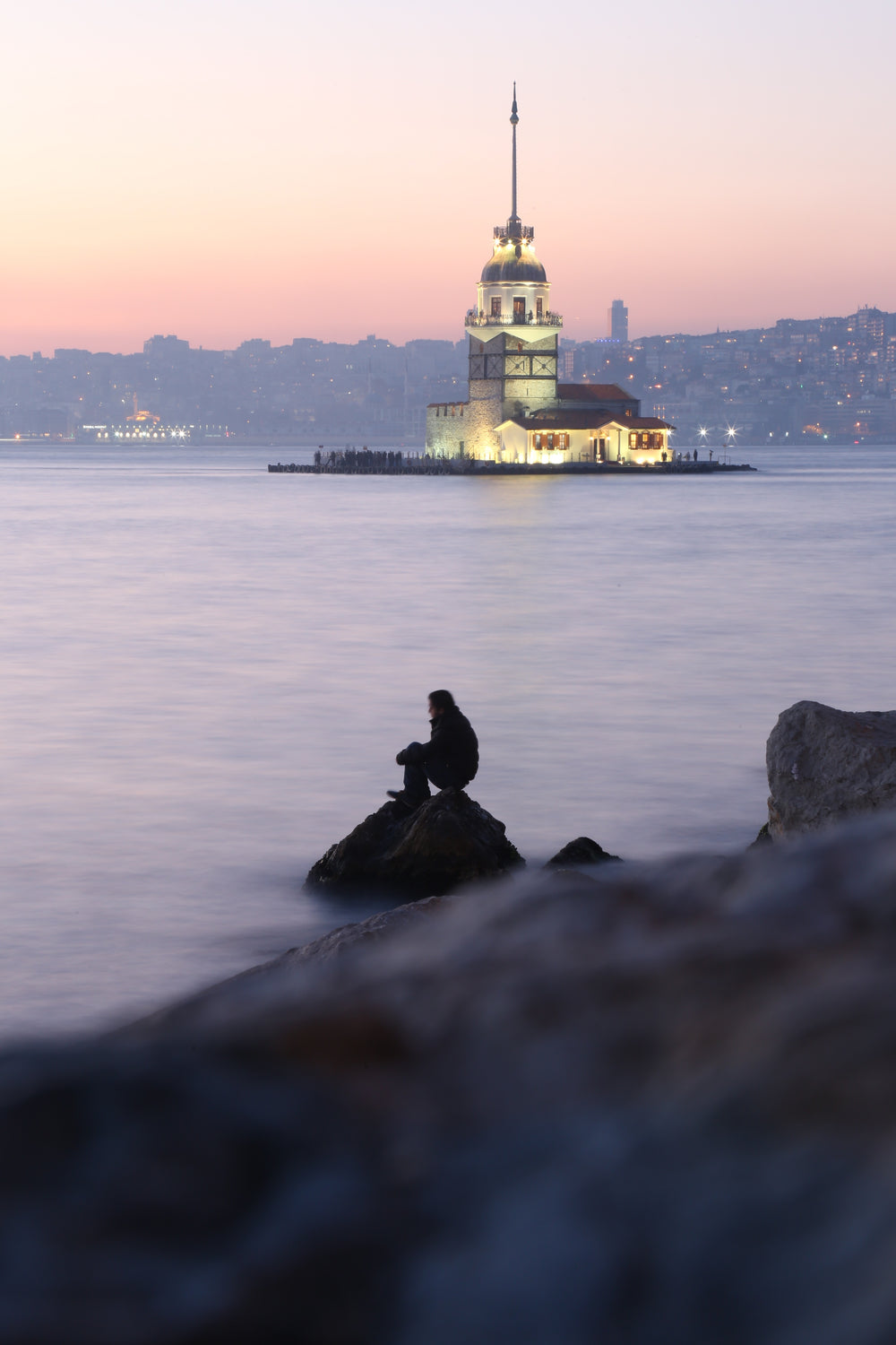 illuminated building over person by a hazy waterfront