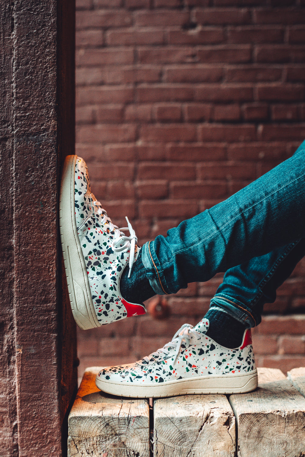 just chilling in white speckled fashion sneakers in alley