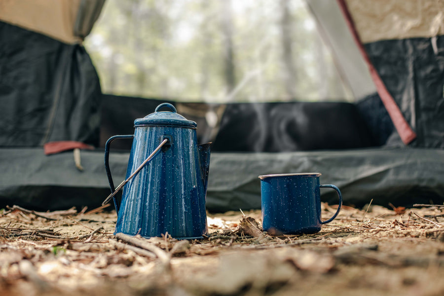 Enamel camp kettle and mug outside a tent