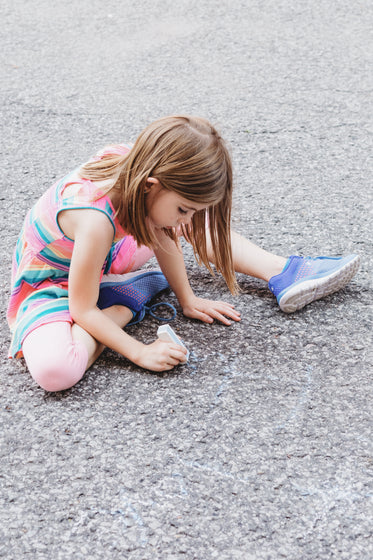 kid draws on ground with chalk