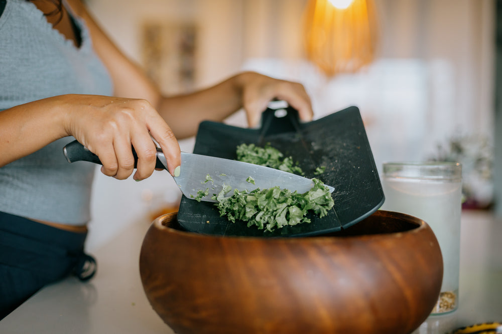 knife scraped kale into wooden bowl