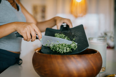 knife scraped kale into wooden bowl