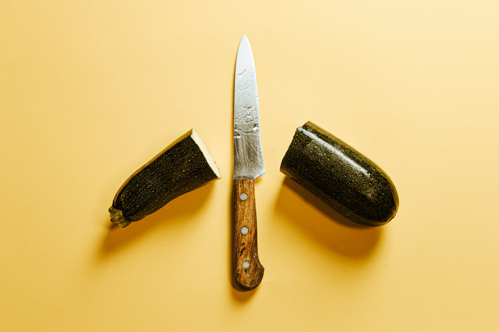 knife with a zucchini cut in half