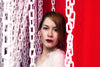 lady in red against a red wall framed by white chains