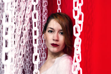 lady in red against a red wall framed by white chains