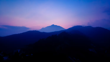 landscape of blue hills and a pink sky at sunset