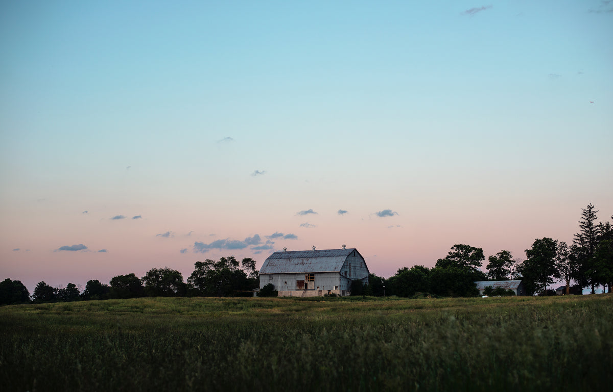 large blue barn in the countryside at sunset